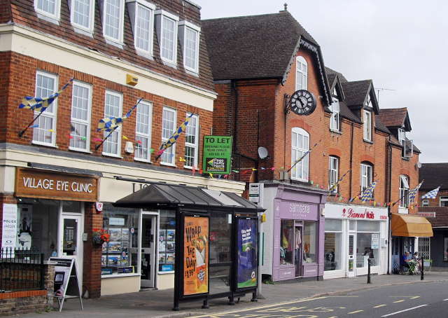 several shops fronts in red brick buildings, with checkered flags. Also a bus shelter in front.