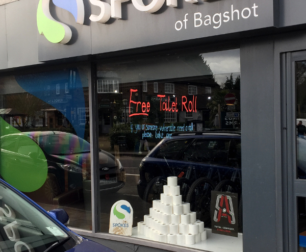 a dark grey shop front with a pile of toilet rolls in the window